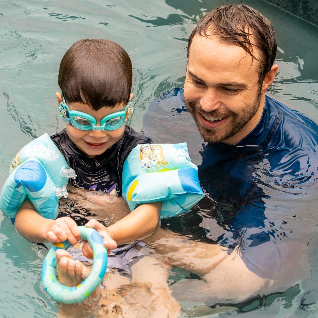 Father and Son in pool with the child wearing the Wahu x Bluey Armbands