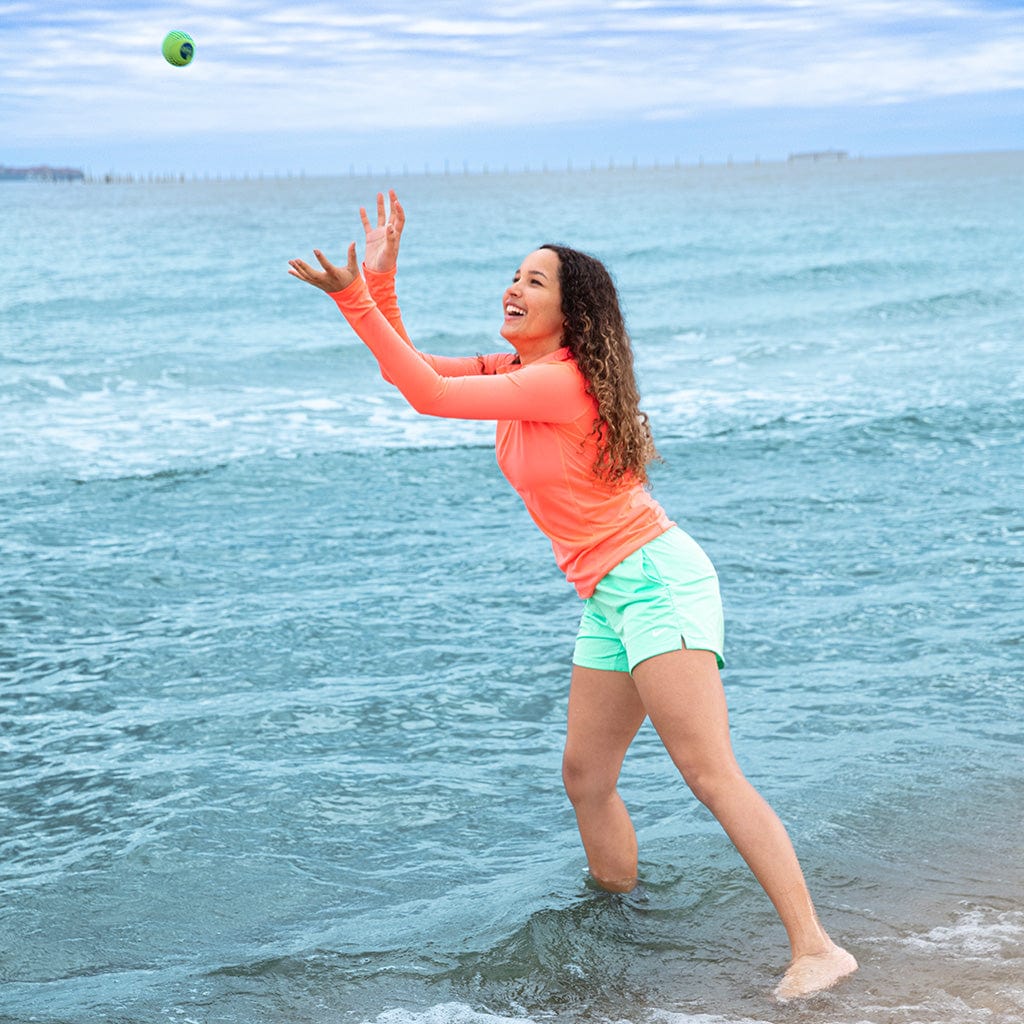 Girl catching green Wahu Super Grip Skimball at beach